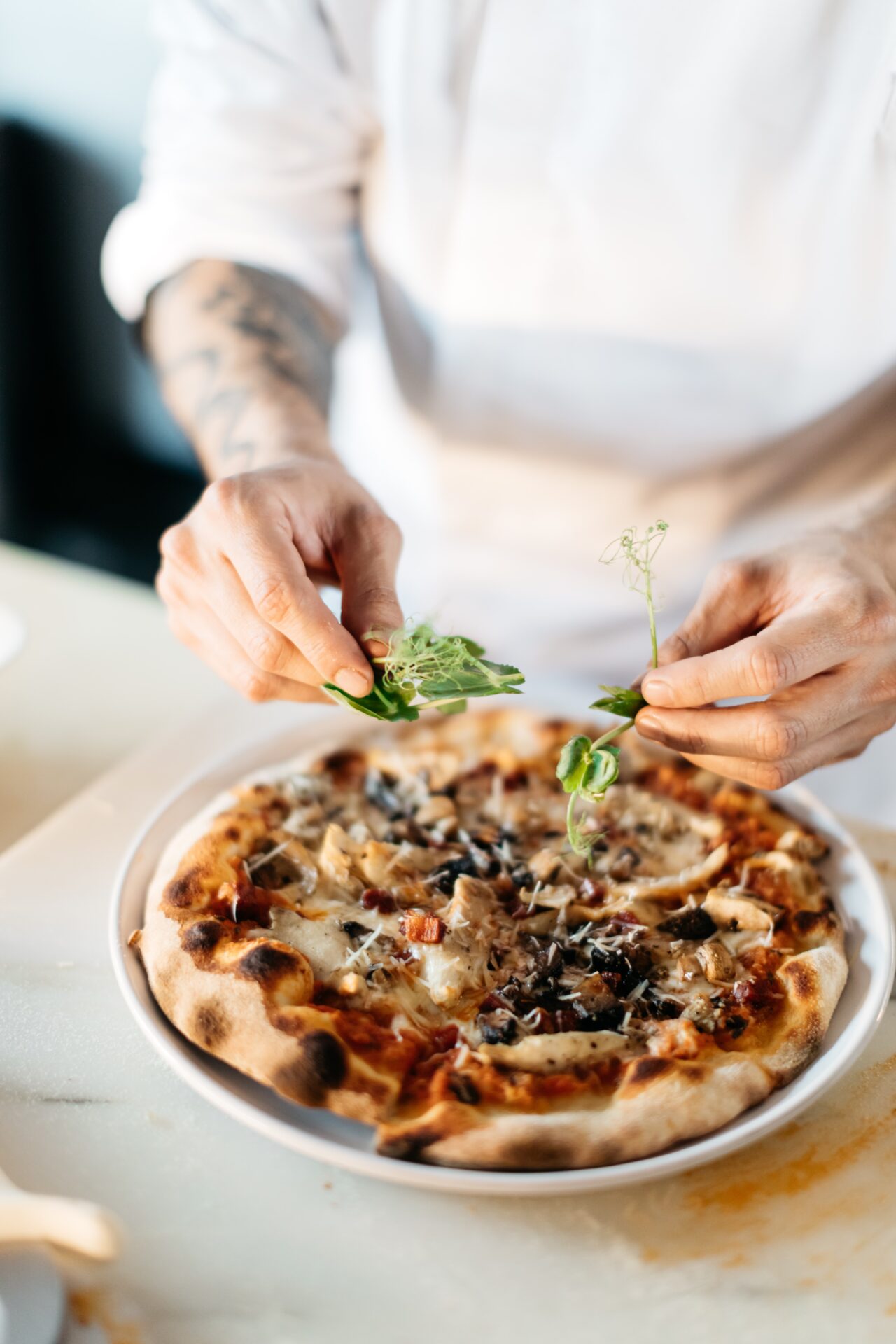 Bilden visar en person som dekorerar en pizza. Pizzaugn, elektrisk variant är ett väldigt bra val för att snabbt komma igång med pizzautbudet i din restaurang.
